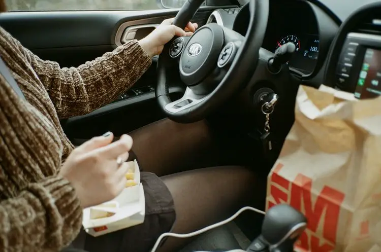 A person driving car with snacks